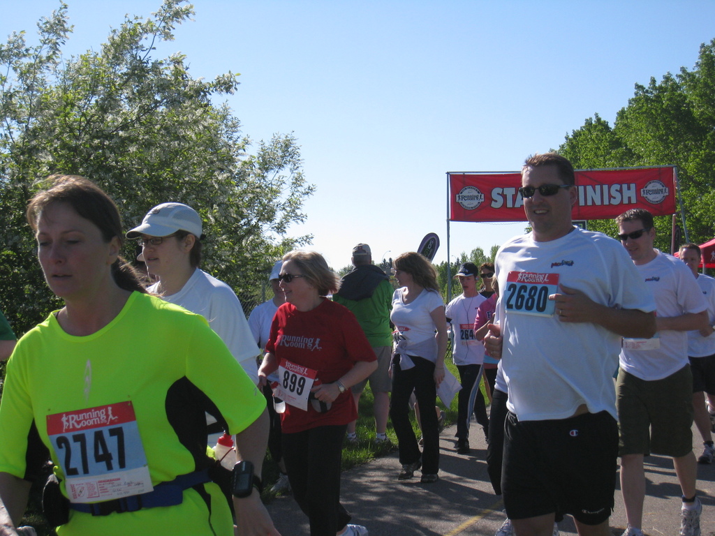 Eine Gruppe von Kindern, die bei einem Marathonlauf laufen, mit einer roten Fahne und Bäumen im Hintergrund.