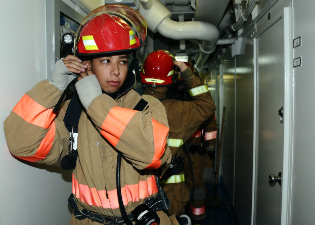 Feuerwehrleute in Uniform in einem Raum mit Rohren und Geräten während eines Übungseinsatzes.