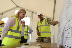 Eine Gruppe von Menschen, einige mit Helmen, sitzt um einen Tisch mit Papieren und einem Buch in einem Zelt.