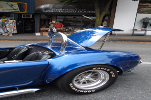 Ein blaues Fahrzeug ist auf der Straße mit Geschäften und Menschen im Hintergrund.