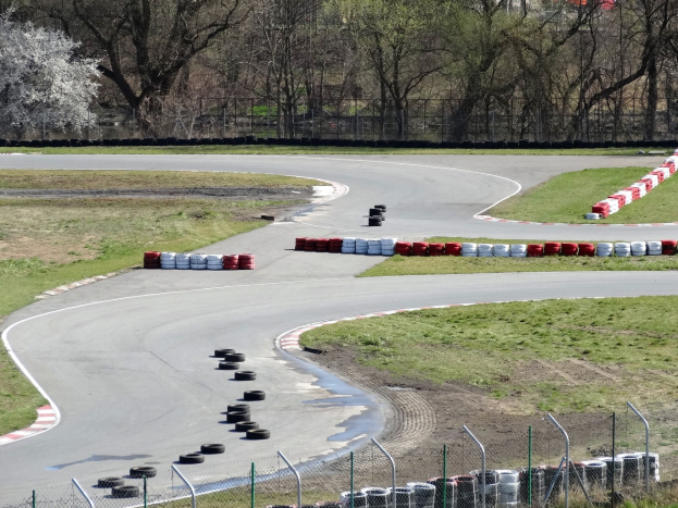 Rennstrecke voller Reifen, umgeben von Gras und Maschendrahtzaun, mit Bäumen im Hintergrund