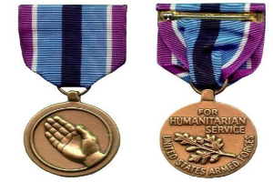 Zwei Medaillen mit lila und blauen Bändchen, mit Text zur Anerkennung humanitärer Dienste.