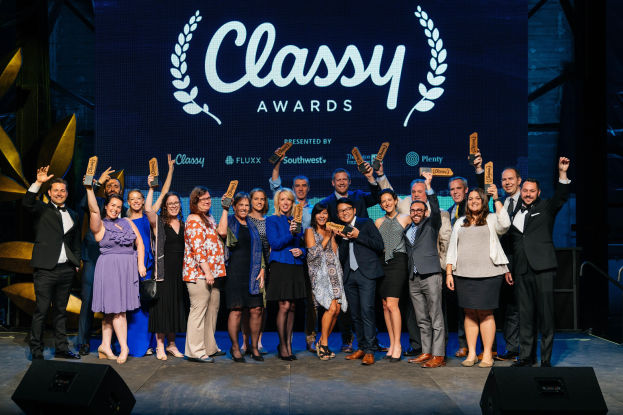 Gruppe von Menschen auf einer Bühne mit Auszeichnungen, mit "Classy Awards 2019" auf einem Bildschirm dahinter.