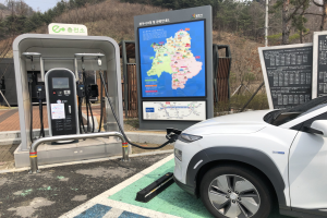 Laden eines Elektroautos an einer Station umgeben von Bäumen unter einem Himmel in Seoul, Südkorea.