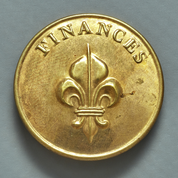 Eine Goldmünze mit einem Fleur-de-lis-Design und dem Wort "Finanzen" auf einem grauen Hintergrund.