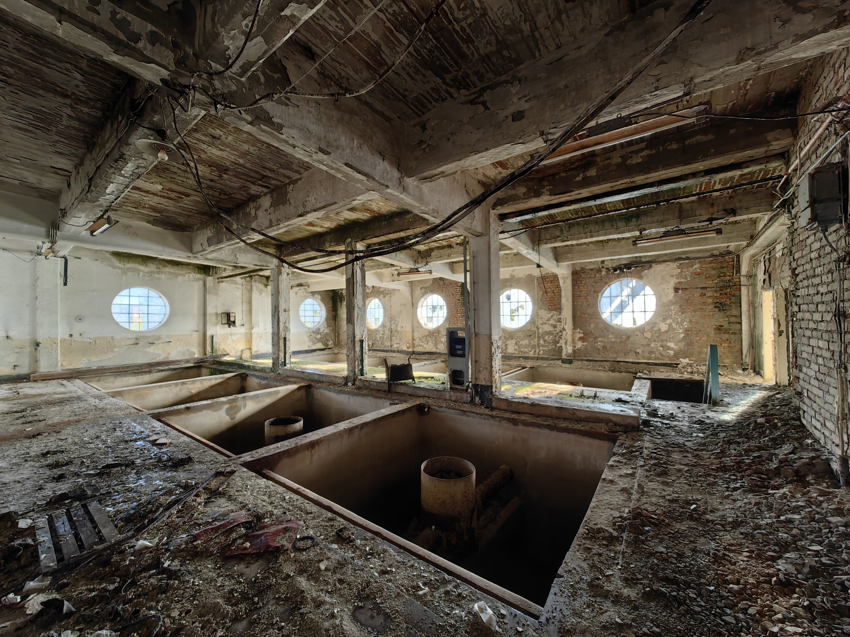 Verlassener Gebäudeinnenraum im Chernobyl-Ausschlussgebiet mit verstreuten Trümmern, freiliegenden Wänden, Decke und strukturellen Elementen.