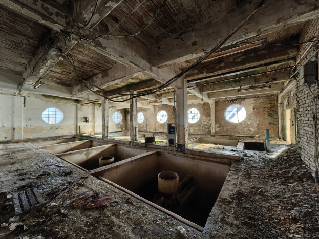 Verlassener Gebäudeinnenraum im Chernobyl-Ausschlussgebiet mit verstreuten Trümmern, freiliegenden Wänden, Decke und strukturellen Elementen.