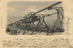 Ein altes Schwarz-Weiß-Foto einer Eisenbahnbrücke mit einem Kran, umgeben von Bäumen und einem bewölkten Himmel, mit dem Text "Bahnstrecka, die erste Eisenbahnbrücke in Deutschland" unten.