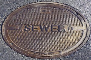 Metall-Schachtobjekt auf der Straße mit dem Wort "Kanal" geprägt.