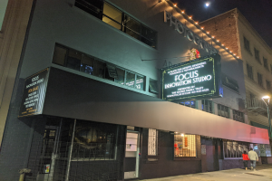 Das Focus Innovation Studio in New York City bei Nacht, mit beleuchteten Gebäuden, Menschen auf dem Gehweg und einem sichtbaren Nachthimmel.