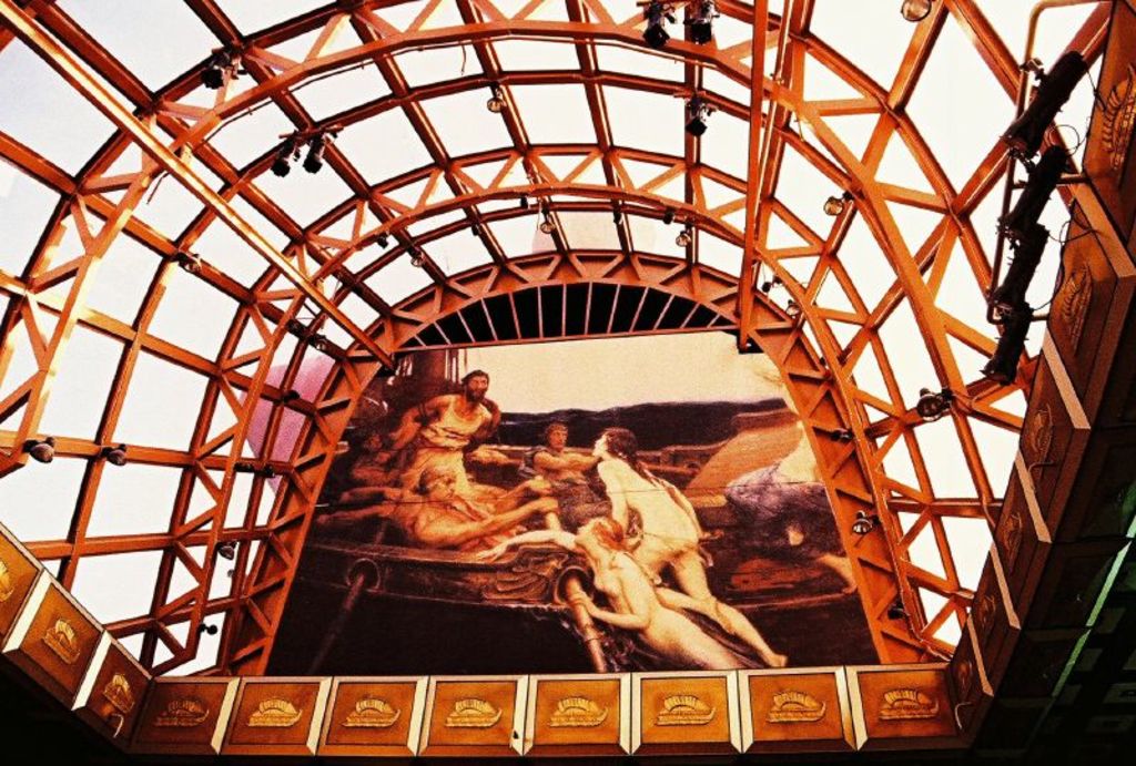 Eiserne Stangen und eine Fahne oder Plakat werden von Scheinwerfern beleuchtet, vor einem Himmel als Hintergrund.