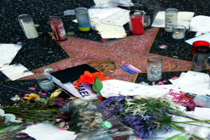 Ein Stern auf dem Hollywood Walk of Fame umgeben von Blumenbouquets, Kerzen, Papieren und anderen Gegenständen.