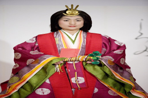 Eine Frau in einem traditionellen japanischen Kimono steht selbstbewusst auf einem Laufsteg und trägt ein leuchtend rotes und grünes Kleid mit aufwändigen Mustern und einem ordentlich zurückgebundenen Dutt.