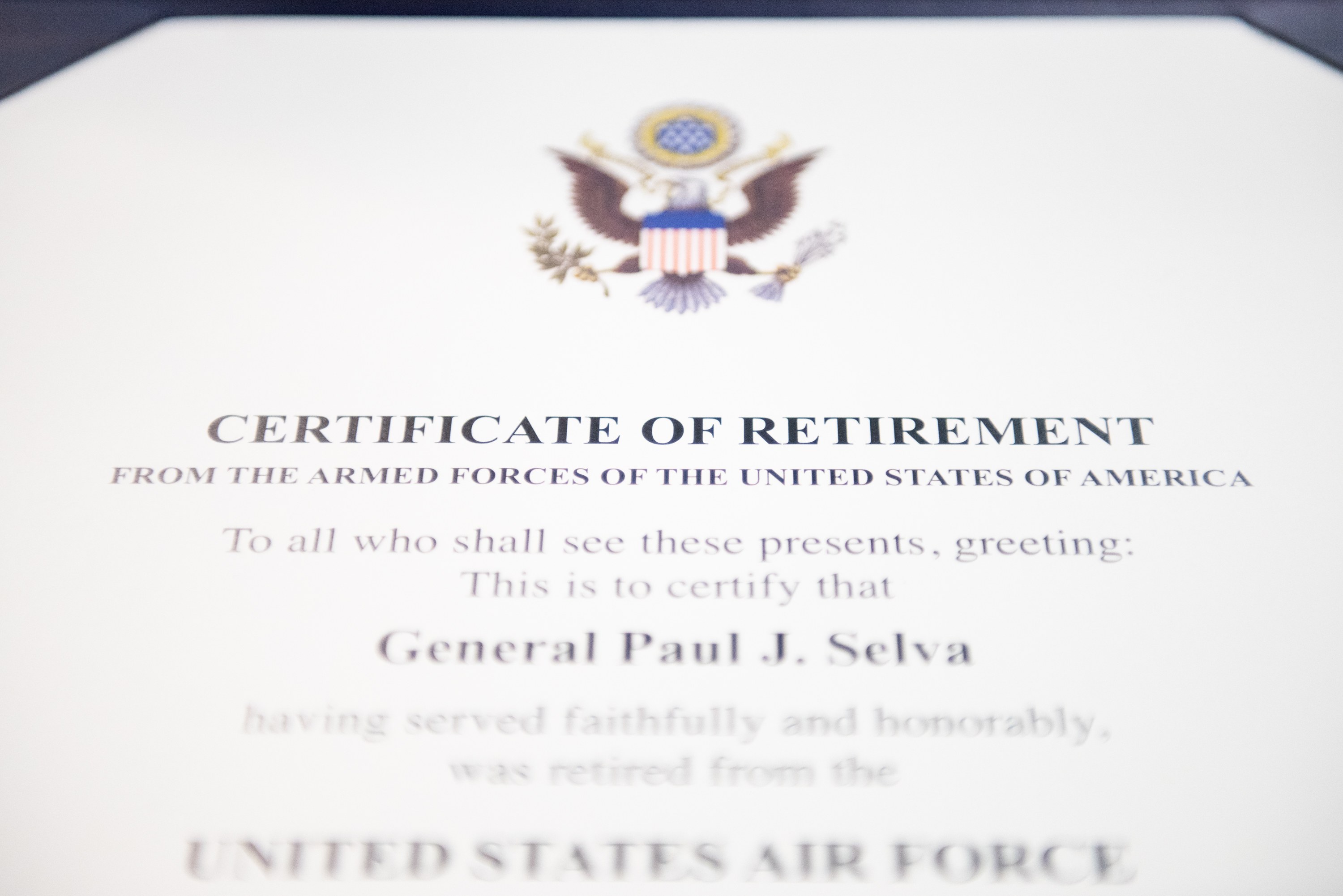 Rahmenurkunde der United States Air Force mit blauer Einfassung, zentralem Sternschild-Logo, umgeben von einem Lorbeerkranz und einer "Retirement"-Banderole, alles in Schwarz gedruckt.