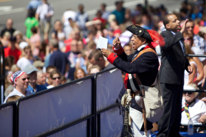 Ein Mann in Piratenkostüm steht auf einer Bühne und hält ein Blatt Papier in der Hand, vor ihm eine Menschenmenge und im Hintergrund unscharfe Geländer.