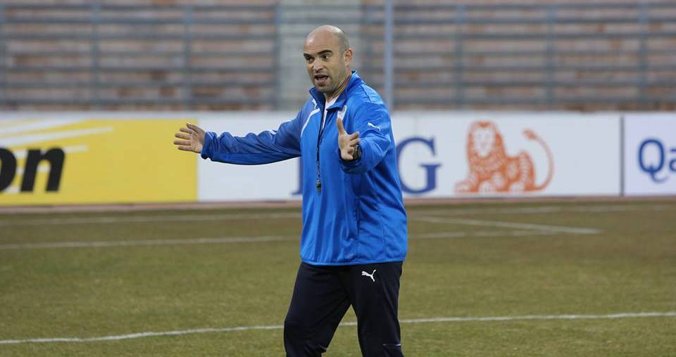 Mann in blauem Jackett auf Fußballfeld mit entschlossener Miene