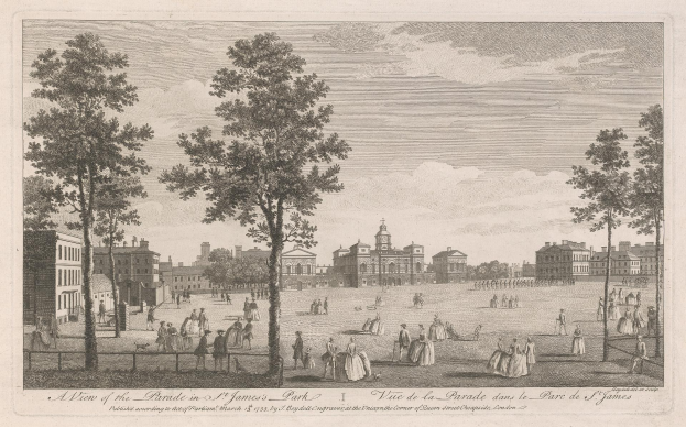 Eine Gruppe von Menschen steht und sitzt im St. James Park während eines Umzugs, mit Bäumen und Gebäuden im Hintergrund unter einem bewölkten Himmel.