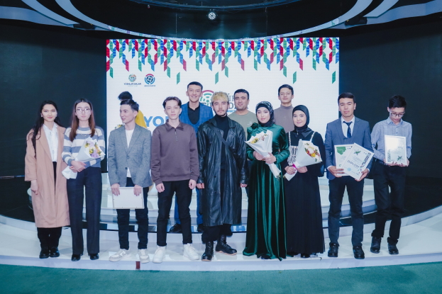 Gruppe von Menschen auf einer Bühne mit Blumensträuschen und Urkunden, mit einem "Youth Solar Awards 2019"-Hintergrund.