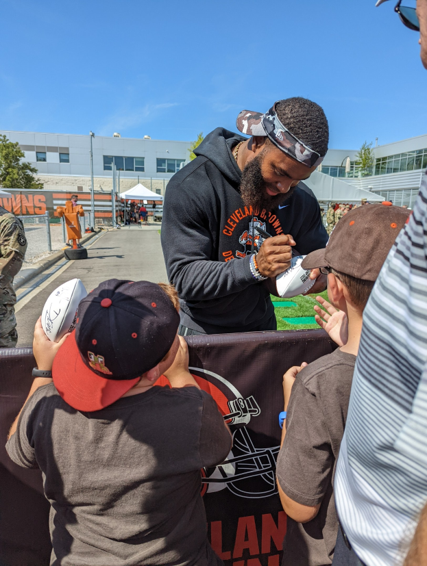 Cleveland Browns Wide Receiver Odell Beckham Jr. signiert Autogramme für Fans vor der Trainingsanlage des Teams, umgeben von Menschen mit Kappen.